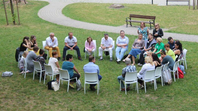 A circle of chairs set out on grass for a group conversation