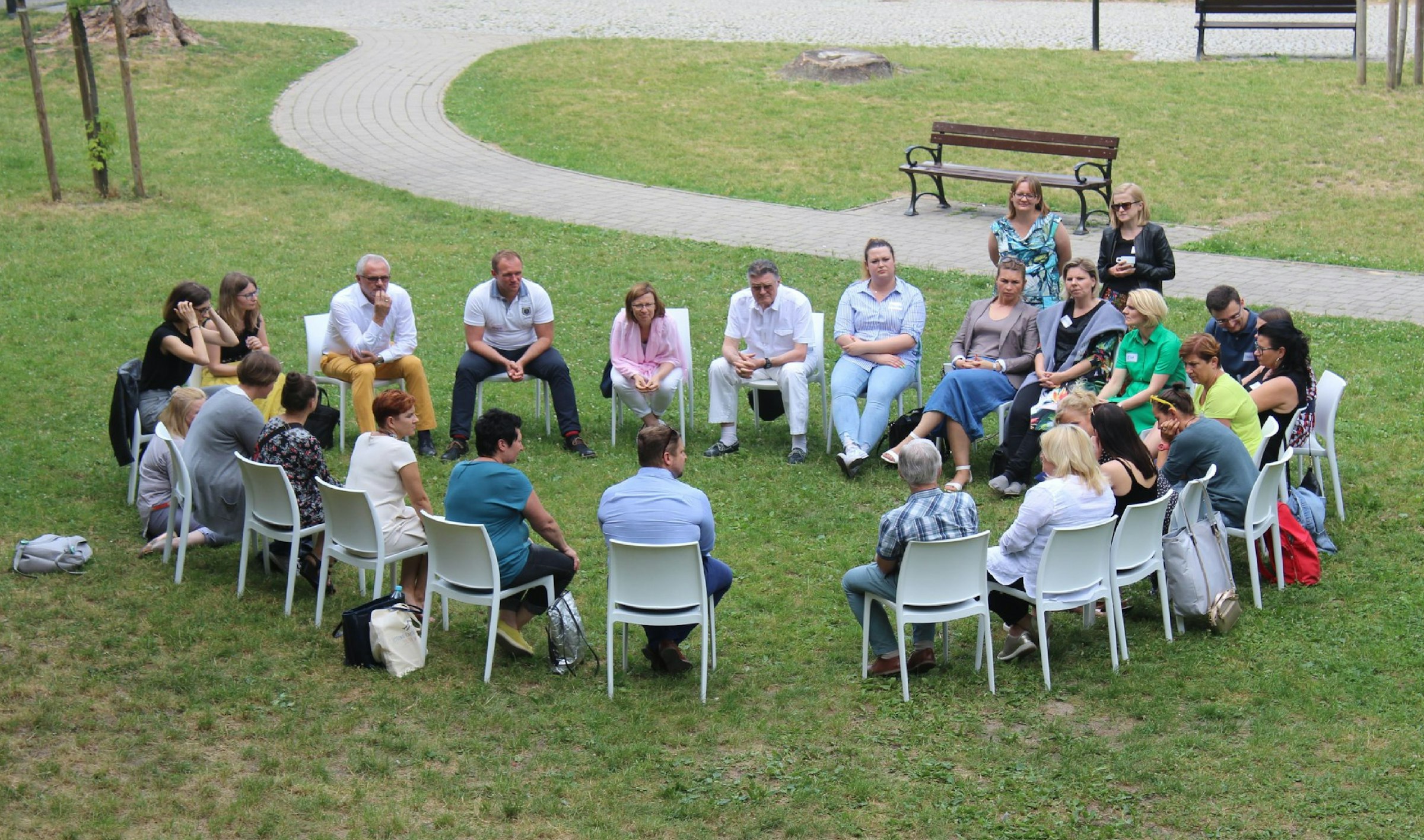 A circle of chairs set out on grass for a group conversation