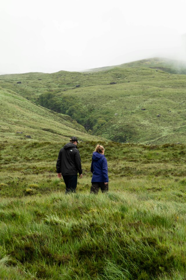Two people walking in misty Scottish hills